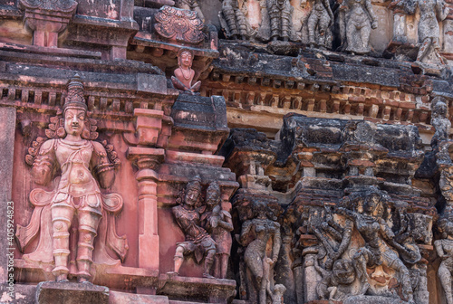 Hampi, Karnataka, India - November 5, 2013: Vijaya Vitthala Temple. Closeup of blackened and damaged statues on red stone Gopuram.