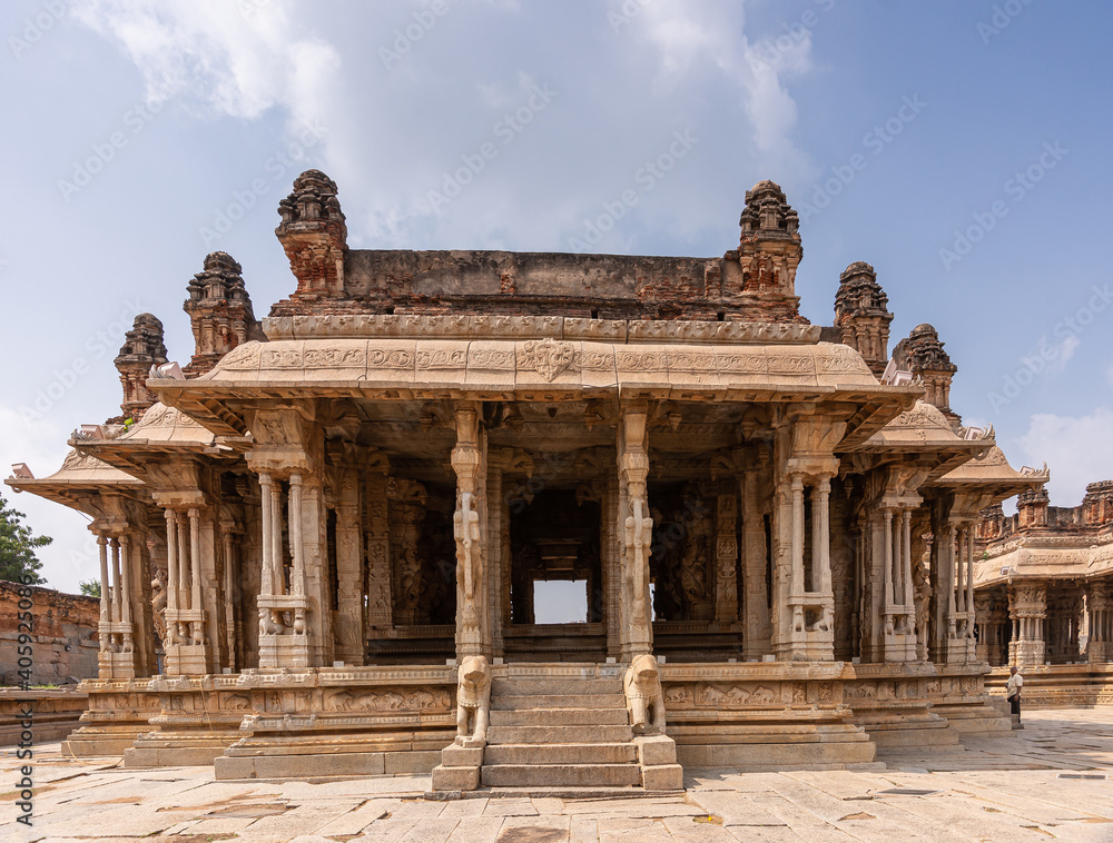 Hampi, Karnataka, India - November 5, 2013: Vijaya Vitthala Temple. Looking straith through brown stone sanctuary with hollow pillars under blue cloudscape.