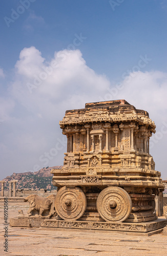 Hampi, Karnataka, India - November 5, 2013: Vijaya Vitthala Temple. Brown stone chariot protrait under blue cloudscape.