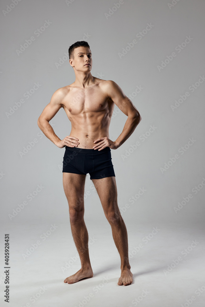 sexy athlete holds hands on a belt in full growth on a gray background bodybuilder sexy athlete holds hands on a belt in full growth on a gray background bodybuilder