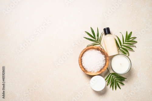 Spa background. Spa product composition with palm leaves, cosmetic and sea salt at stone table. Flat lay image.