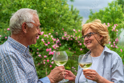 Senior man and lady holding, clinking glasses and drink wine. Communication, friendly laughter, relationship.