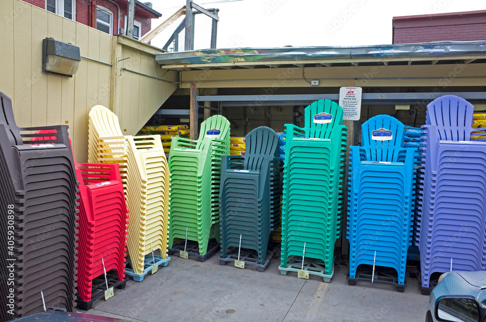 Array stacks of multicolored plastic Adirondack like summer lawn deck patio backyard chairs waiting. St Paul Minnesota MN USA