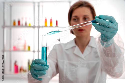 The laboratory assistant holding test tube, pipetting liquid
