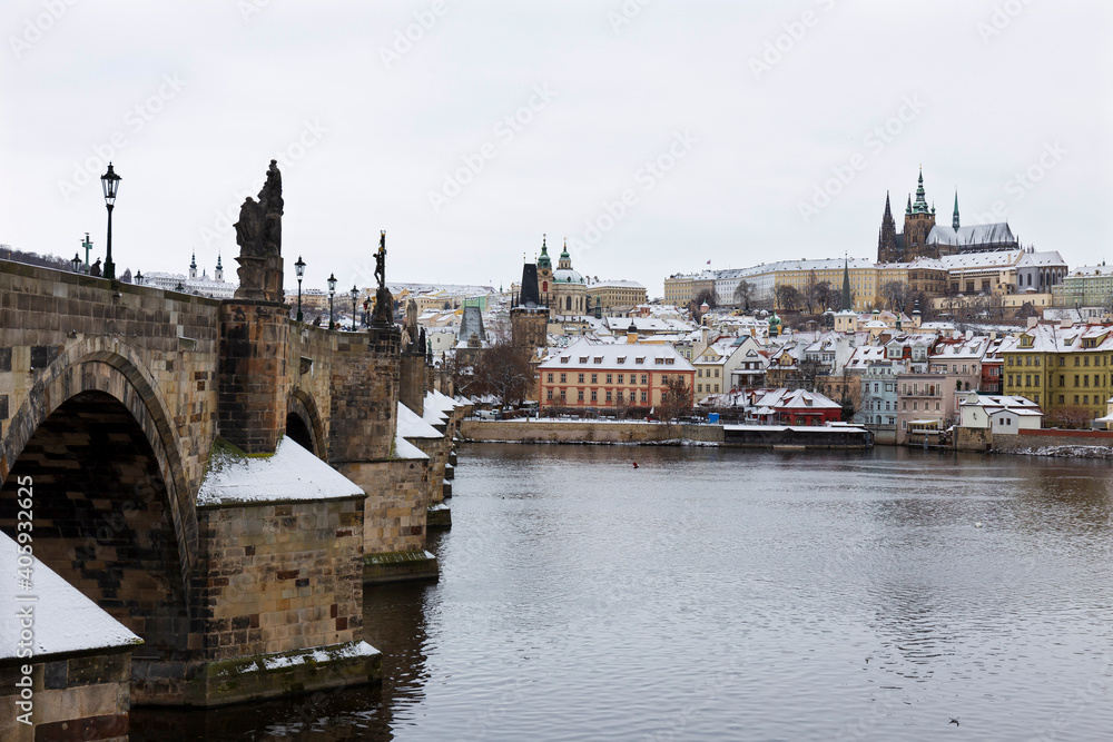 Fototapeta premium Snowy Prague Lesser Town with Prague Castle and Charles Bridge above River Vltava, Czech republic