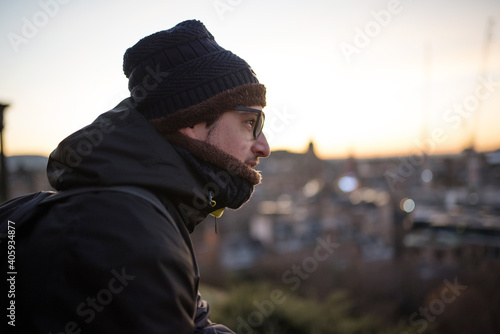 Young man in profile, warm in winter clothes, contemplating the landscape