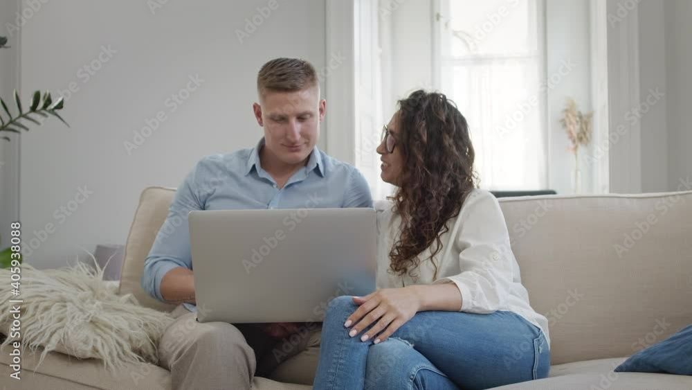 Young Couple On Sofa Looking At Something In Laptop. Young Couple On Sofa Looking At Something In Laptop.
