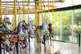 Carousel horses sitting empty at an indoor merry go round carousel in Spokane, Washington with the park and Spokane River blurred in the distance