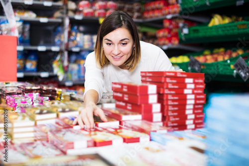 Happy young shopper searching for sweets in supermarket