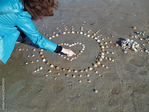 The girl puts a heart made of shells on sand3