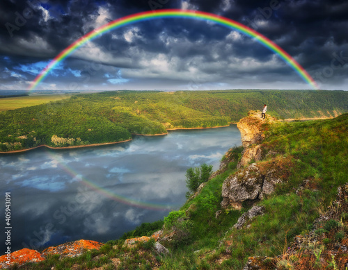 rainbow over the river. woman on a cliff above the canyon 