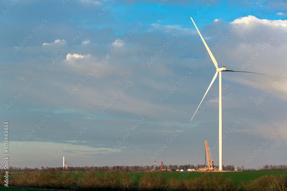 construction of wind turbines in an open space on a field with green grass and fresh wind, engineering equipment with cranes for the installation of windmills. construction of wind turbines in an open space on a field with green grass and fresh wind, engineering equipment with cranes for the installation of windmills.