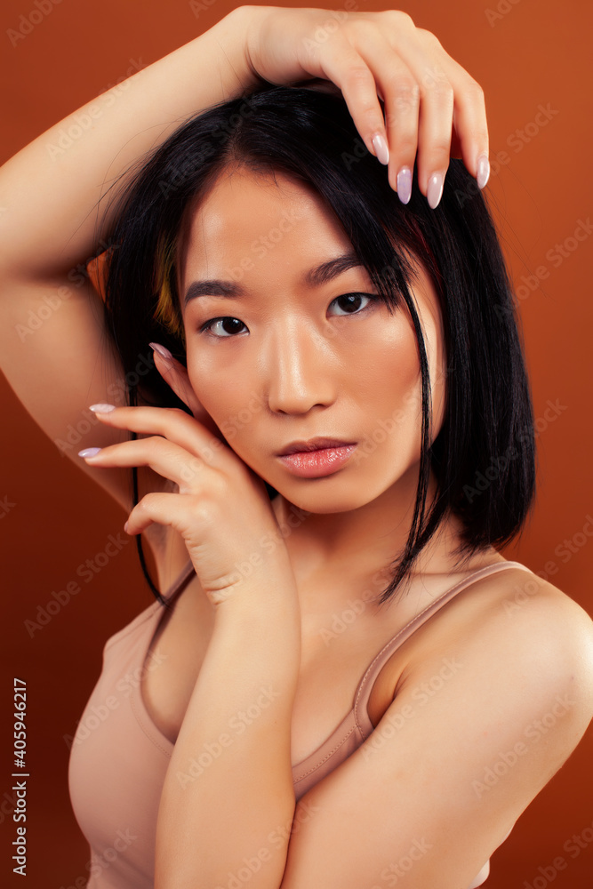 young pretty asian woman cheerful smiling posing on warm brown background, lifestyle people concept