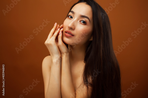young pretty asian woman cheerful smiling posing on warm brown background  lifestyle people concept