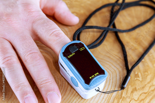 Young woman using pulse oximeter to measure oxygen saturation, treatment at home