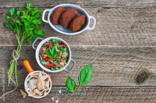 Table served with middle eastern traditional dishes. Bowl with falafel, vegetarian pita, tabbouleh bulgur salad. Top view. Space for text.