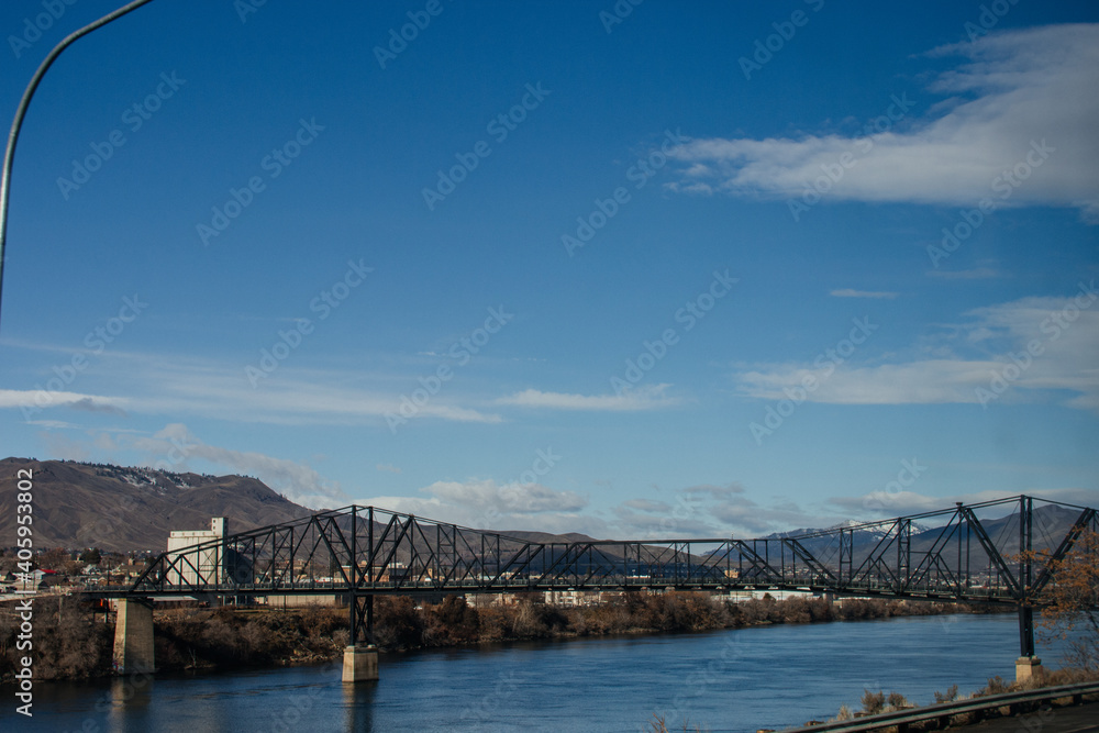 A large metal bridge over a river in a small American town in Washington state. Autumn sunny day with a bright blue sky. 02-08-2020, Washington, USA A large metal bridge over a river in a small American town in Washington state. Autumn sunny day with a bright blue sky. 02-08-2020, Washington, USA