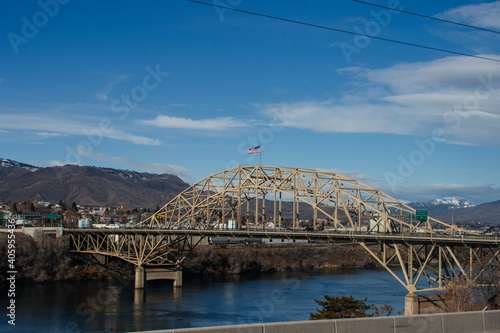A large metal bridge over a river in a small American town in Washington state. Autumn sunny day with a bright blue sky. 02-08-2020, Washington, USA