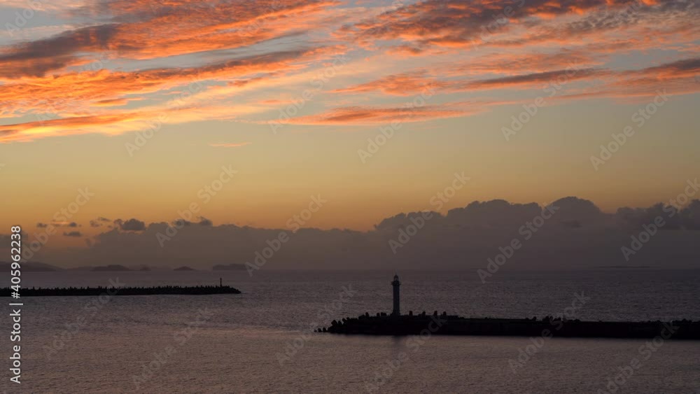 silhouette of a lighthouse against the backdrop of a bright orange, pink sunset. port lighthouse on the background of the ocean surface reflection of orange clouds silhouette of a lighthouse against the backdrop of a bright orange, pink sunset. port lighthouse on the background of the ocean surface reflection of orange clouds