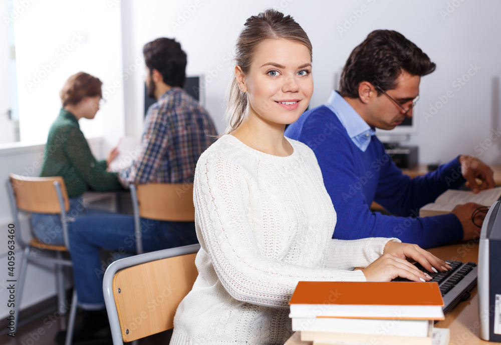 Fototapeta premium female student reading textbook while studying in university computer class