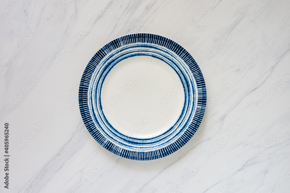 Empty plate with blue round design on marble tabletop, food background