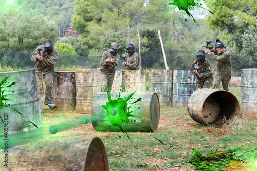 Dynamic paintball battle. Group of players in full paintball equipment attacking opposite team