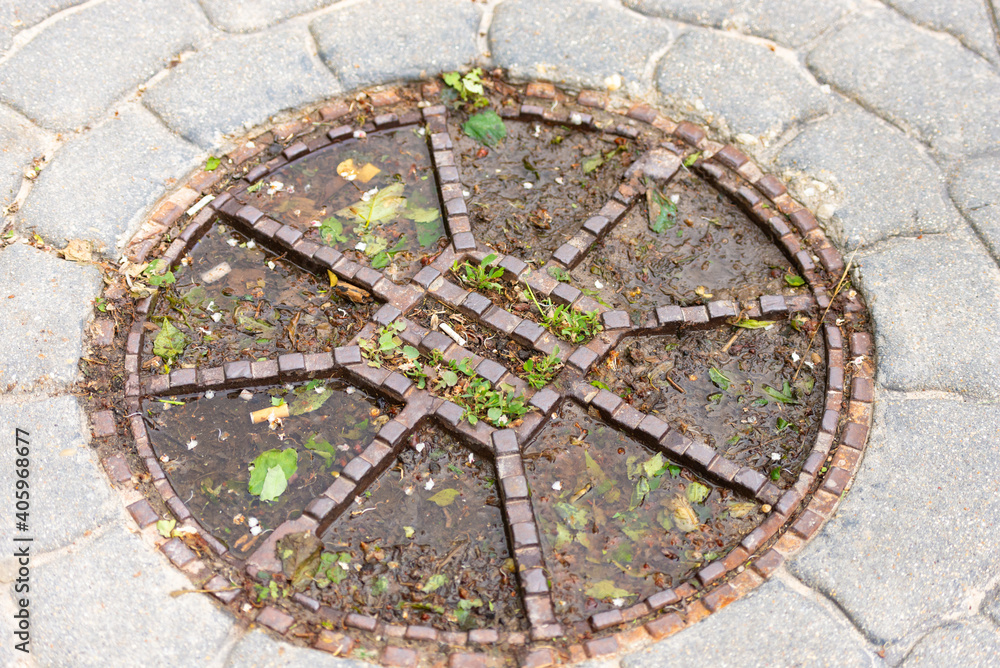 Manhole cover in Bratislava. An old manhole with the remains of leaves, cigarettes and water