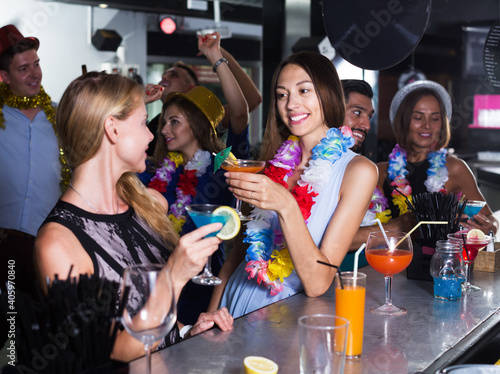 Young women are drinking cocktails on hawaiian party in bar