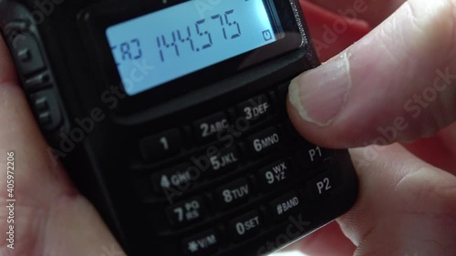 Handheld radio tuning into different frequencies and listening to broadcasts