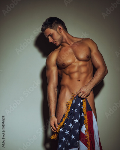 Naked handsome fitness guy standing against the wall with American flag photo