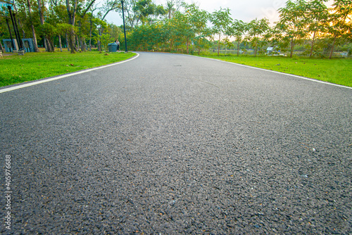 Asphalt walk and running pathway in green city park sunset