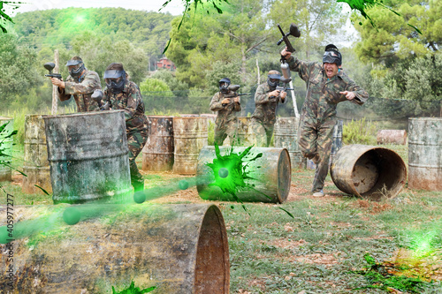Paintball players aiming and shooting with a guns at an opposing team outdoors