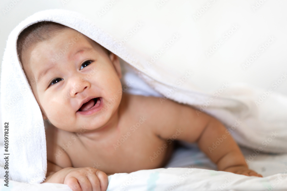 Portrait of happy smile asian baby boy relaxing looking at camera under towel after bath. Cute asian newborn child on the bed at home Portrait of happy smile asian baby boy relaxing looking at camera under towel after bath. Cute asian newborn child on the bed at home
