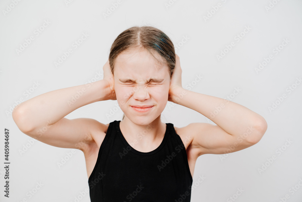 A girl with collected hair in a black T-shirt stands on a white background, covers ears with hands from the loud sound and closes eyes. place for the inscription. quarrels and scandals in the family. A girl with collected hair in a black T-shirt stands on a white background, covers ears with hands from the loud sound and closes eyes. place for the inscription. quarrels and scandals in the family.