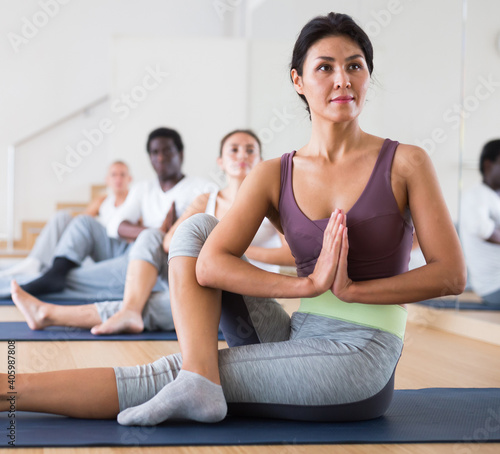 Adult people exercising during yoga class in modern fitness center