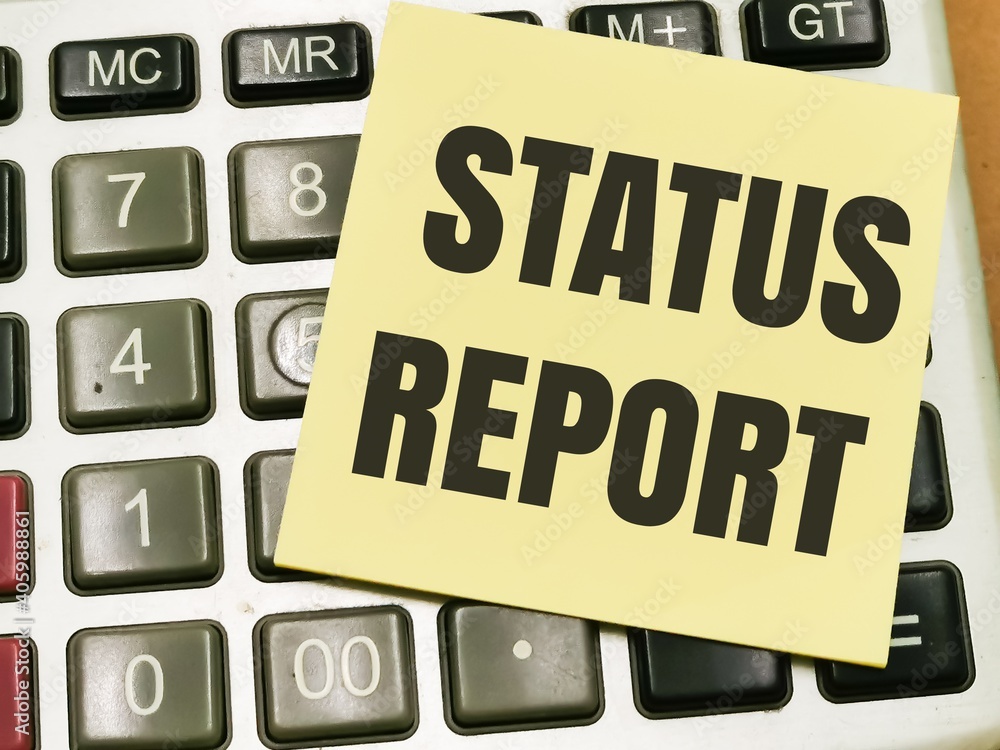 Text STATUS REPORT written on yellow paper note on calculator.Business concept. Text STATUS REPORT written on yellow paper note on calculator.Business concept.