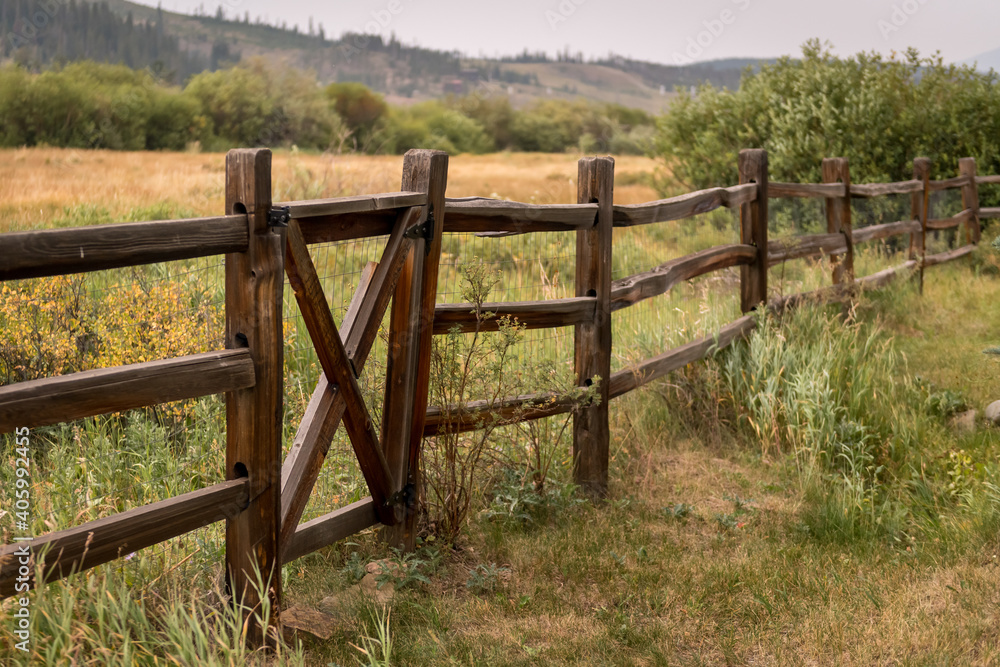 Old fence in Colorado overlooking a pasture of grass and trees