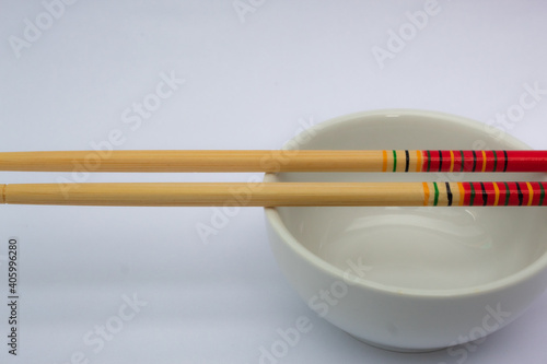 Chopsticks and a white and empty bowl.