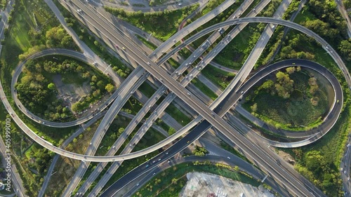4K. Aerial view of road interchange or highway intersection with busy urban traffic speeding on the road. Junction network of transportation taken by drone.