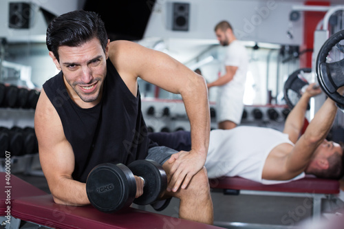 Portrait of handsome athletic man exercising with dumbbells in gym