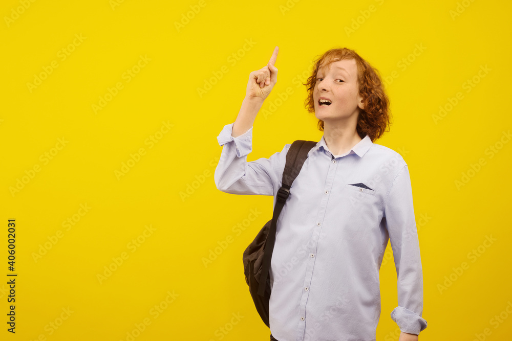 Empty space for text. Yellow background. A teenage boy holds his index finger up. Empty space for text. Yellow background. A teenage boy holds his index finger up.