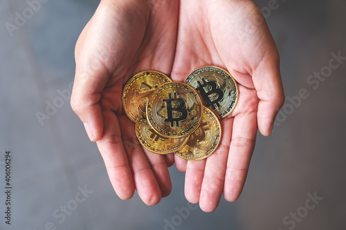 Top view image of a woman holding and showing golden color bitcoins in hands