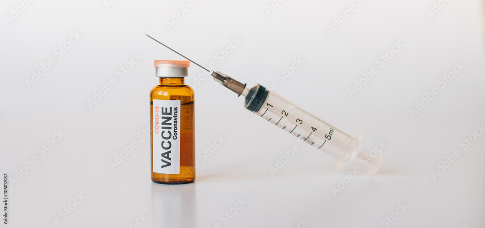 Coronavirus covid-19 vaccine vial with label, syringe for injection on white background with copy space. Medical needle lies on the bottle with drug. Vaccination, immunization concept. Coronavirus covid-19 vaccine vial with label, syringe for injection on white background with copy space. Medical needle lies on the bottle with drug. Vaccination, immunization concept.