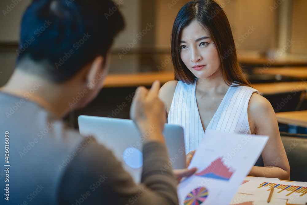 Rear view of Furious boss scolding Asian young businesswoman in casual suit by point to her face about performance and KPI in modern office, Business mistake and punish concept