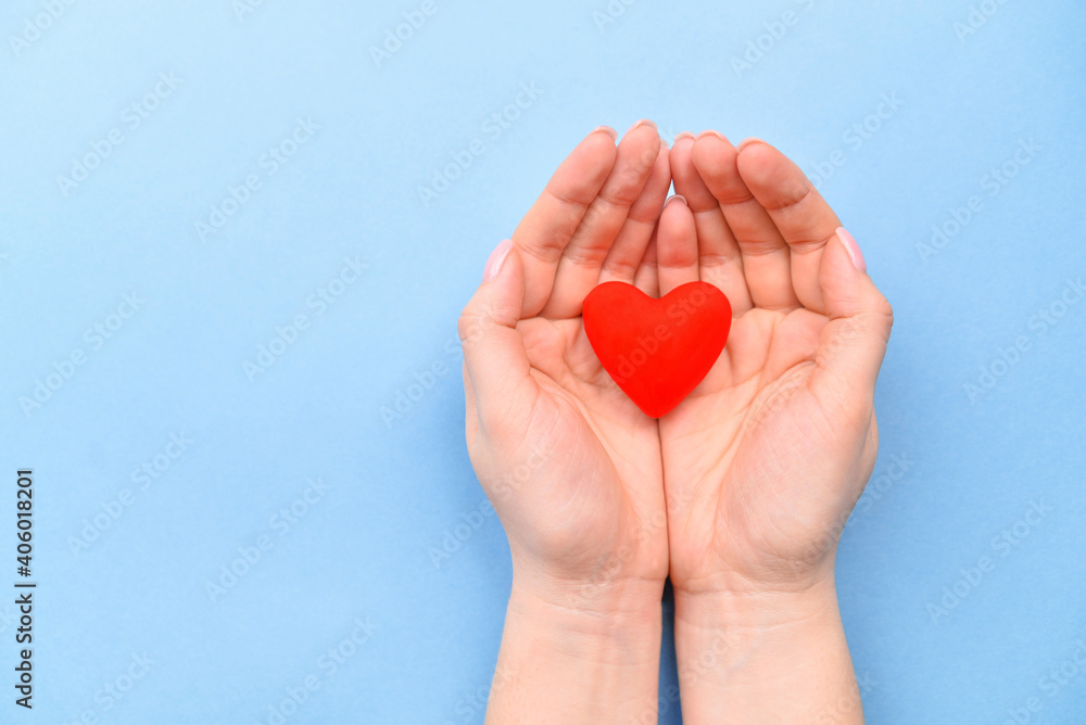 Red symbol heart in hands on a blue background. The concept of Valentine's Day and Women's Day. Top view, place for text. a life. Red symbol heart in hands on a blue background. The concept of Valentine's Day and Women's Day. Top view, place for text. a life.