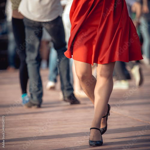 people are dancing outdoors in the park at sunny day. beautiful female feet in dancing shoes in the foreground and red skirt