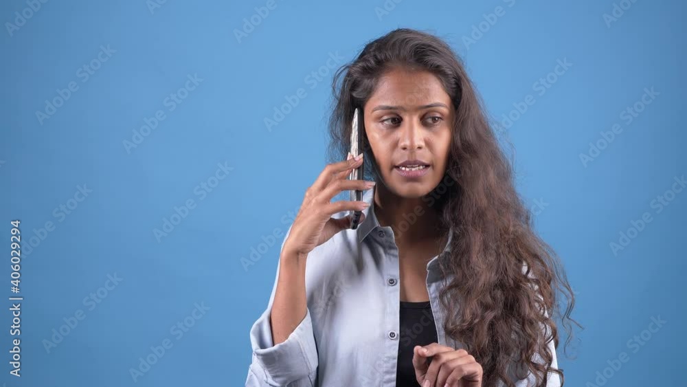 Smiling cheerful young girl Talking on mobile cell phone.posing isolated on blue color background studio.People emotions lifestyle concept. Talking on mobile cell phone looking aside. Smiling cheerful young girl Talking on mobile cell phone.posing isolated on blue color background studio.People emotions lifestyle concept. Talking on mobile cell phone looking aside.