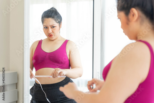 asian fat women , Fat girl , Chubby, overweight plus size looking the mirror measuring her waist in the bedroom - lifestyle Woman diet weight loss overweight problem concept