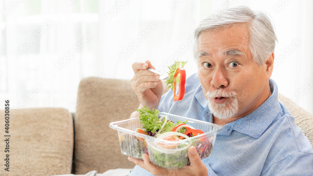 Lifestyle Asian senior man ,old man feel happy enjoy eating diet food fresh salad on sofa Lifestyle Asian senior man ,old man feel happy enjoy eating diet food fresh salad on sofa