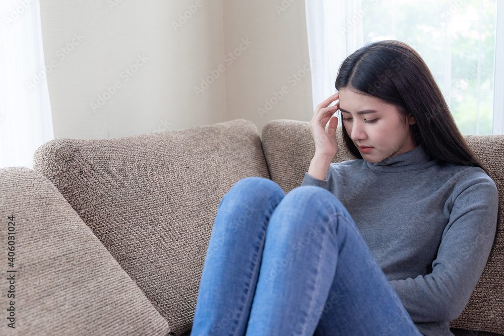 Close up face of unhappy Asian pretty young woman sitting alone on couch with feeling sadness Close up face of unhappy Asian pretty young woman sitting alone on couch with feeling sadness